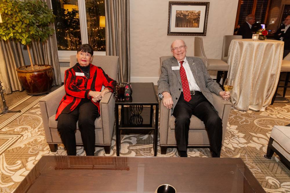 Two reception guests sitting in chairs smiling at camera